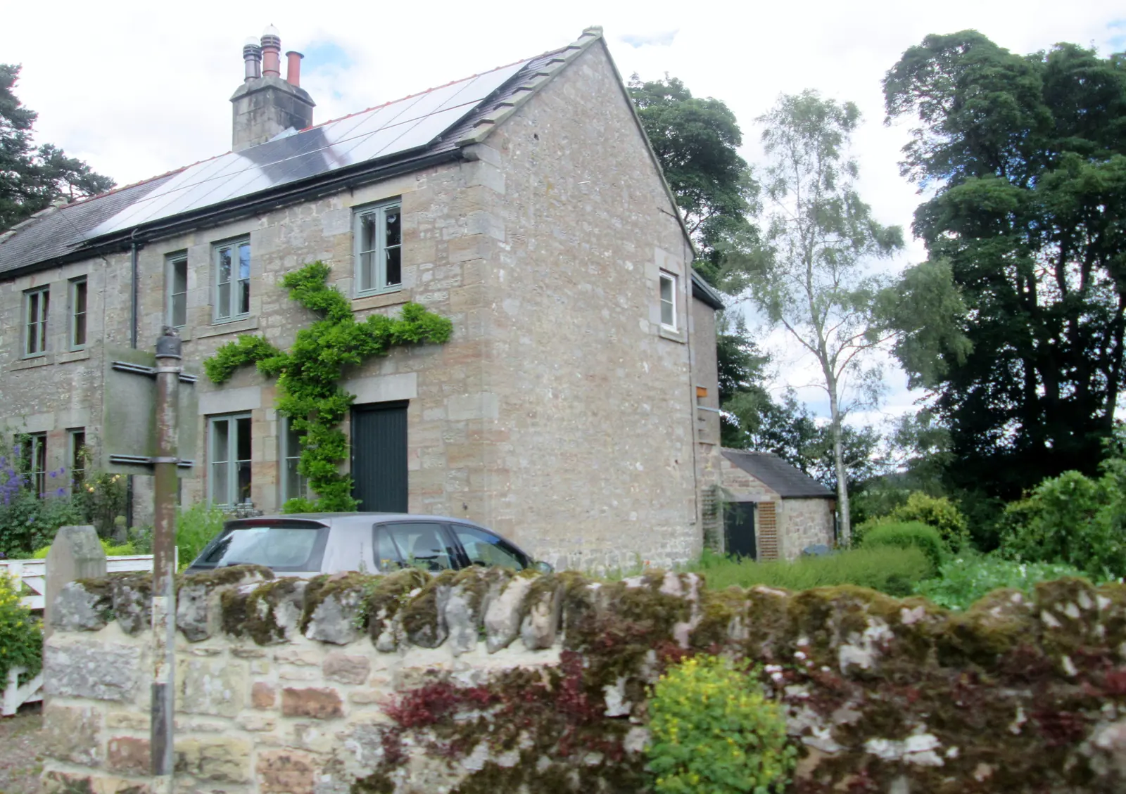 A stone-built house with solar panels on its pitched roof