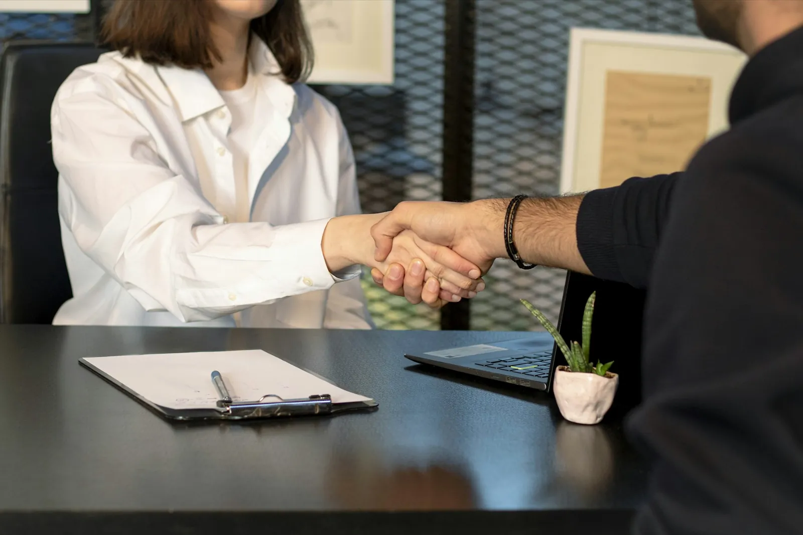 Two people shaking hands across a desk after a consultation